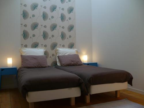 two twin beds in a room with two lamps at Gites Gayet in Saint-Androny