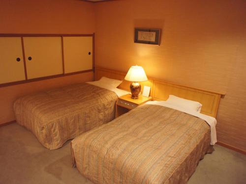 una habitación de hotel con 2 camas y una lámpara en Usyounoie Sugiyama en Gifu