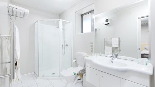 a white bathroom with a shower and a sink at Arthur's Court Motor Lodge in Christchurch