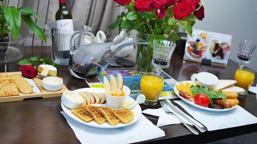 a table with plates of food and drinks and roses at Arthur's Court Motor Lodge in Christchurch