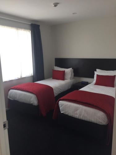 a room with two beds with red and white sheets at Rolleston Highway Motel in Rolleston