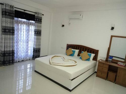 a bedroom with a large white bed with a heart shapedvisorvisorvisor at White Lion Paradise Dikwella in Batigama