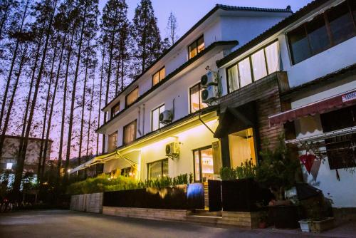 een groot wit gebouw met bomen op de achtergrond bij MK Inn in Hangzhou