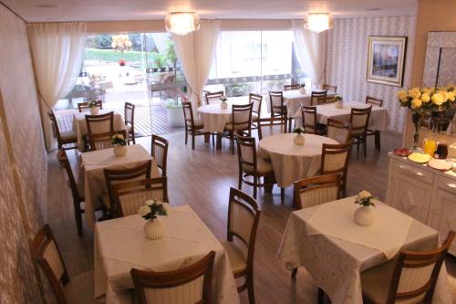 um restaurante com mesas e cadeiras com toalha de mesa branca em Pousada Suisse em Campos do Jordão
