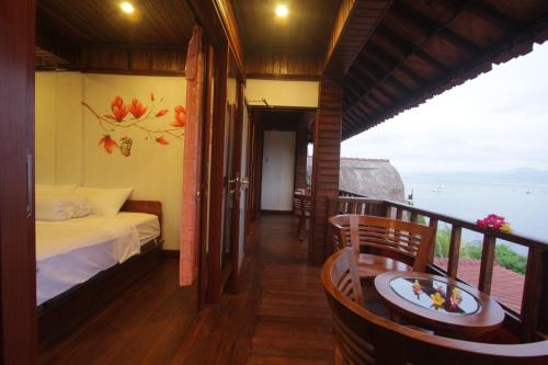 een kamer met een bed, een tafel en een balkon bij Dava Villa Ocean View in Nusa Penida