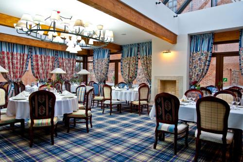 a dining room with tables and chairs and a chandelier at Hotel St. Bruno in Giżycko