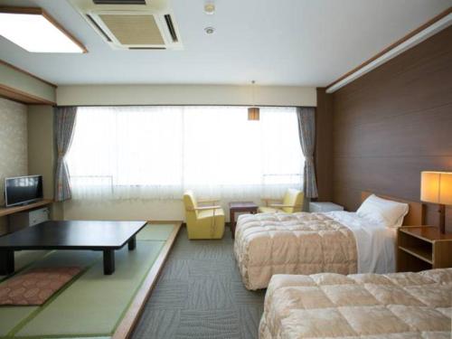 a hotel room with two beds and a table at Ikaho Grand Hotel in Shibukawa