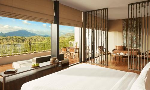 a bedroom with a bed and a balcony with a view at Jetwing Lake in Dambulla