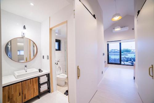 Baño blanco con lavabo y espejo en Wooyeon Handong Private Pension en Jeju