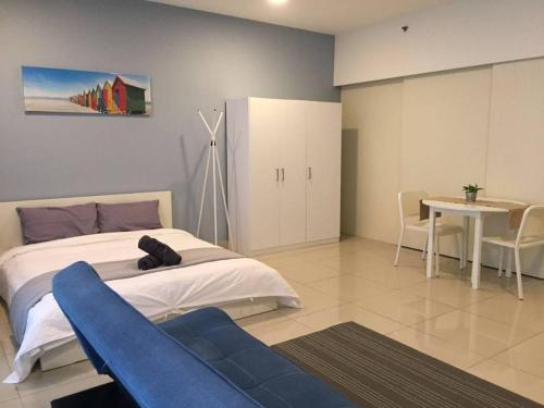 ein Schlafzimmer mit einem großen Bett und einem blauen Sofa in der Unterkunft 34 Studio at Trefoil Setia Alam in Shah Alam