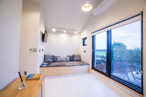 een kamer met een stoel bij het raam met uitzicht op de oceaan bij Wooyeon Handong Private Pension in Jeju-stad