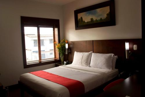 - une chambre avec un lit doté d'une couverture rouge et d'une fenêtre dans l'établissement Hotel AW Boutique, à Bogotá