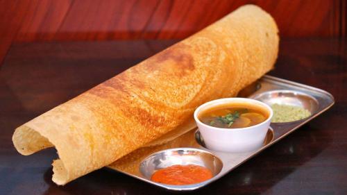 a plate of food with a burrito and two dipping sauces at Blackroots Serviced Apartments in Coimbatore