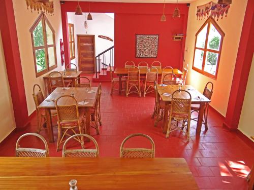 a dining room with tables and chairs and red walls at Chrissie's Hotel in Thekkady