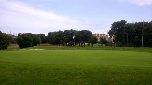 um campo de golfe com um buraco no meio de um campo verde em Cómodo Apt 40m playa . em Noja