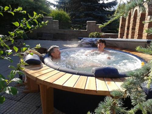 two men laying in a hot tub in a backyard at Apartments České Středohoří in Teplice