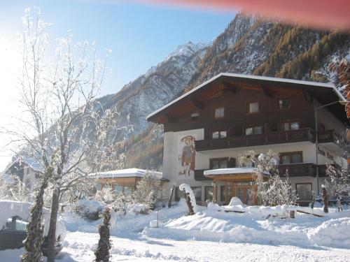 a large building in the snow in front of a mountain at Pension Bäuerle in Heiligenblut