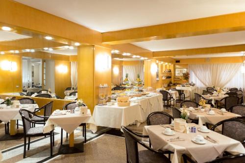 un restaurant avec des tables, des chaises et des nappes blanches dans l'établissement Best Western Hotel Libertà, à Modène