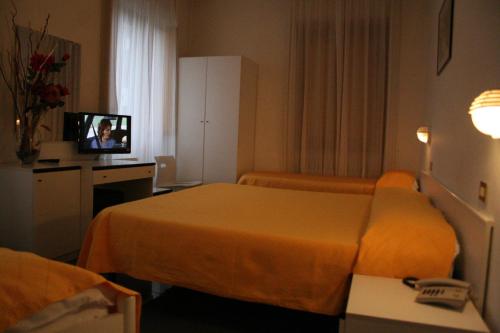 a hotel room with two beds and a television at Hotel La Meridiana in Anghiari