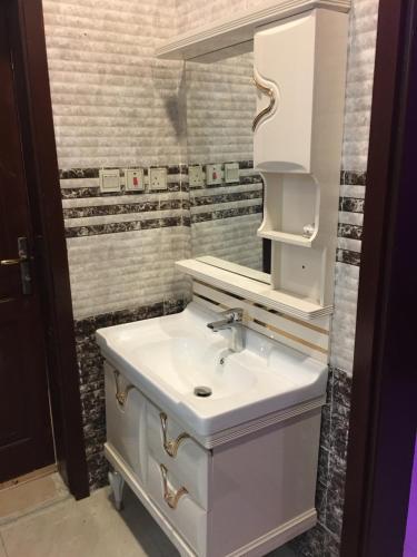 ein Badezimmer mit einem weißen Waschbecken und einem Spiegel in der Unterkunft اوركيدا طريف Orchida Turaif 2 2 in Turaif