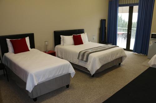 a bedroom with two beds with red pillows at Dante Deo Guesthouse in Bloemfontein