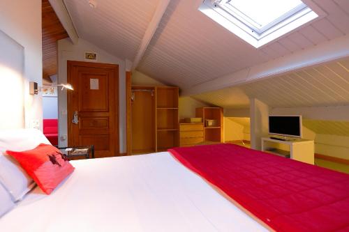 a bedroom with a large white bed and a skylight at La Ermita de Deva in Deva