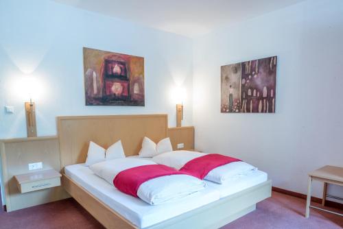 a bedroom with a bed with white and red sheets at Hotel Kärntnerhof in Mallnitz