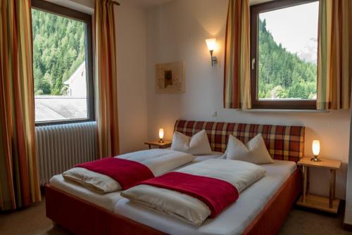 a bedroom with a large bed with two windows at Hotel Kärntnerhof in Mallnitz