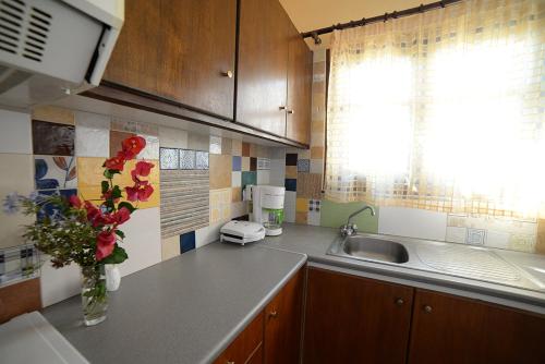 una cocina con fregadero y un jarrón de flores en Koundouros Vacation Homes, en Koundouros