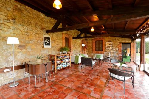 a living room with chairs and tables and a stone wall at La Ermita de Deva in Deva