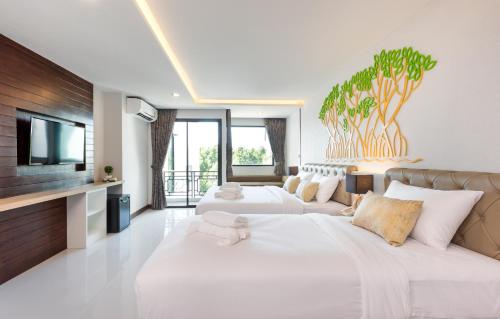 a hotel room with two beds and a flat screen tv at River Front Krabi Hotel in Krabi