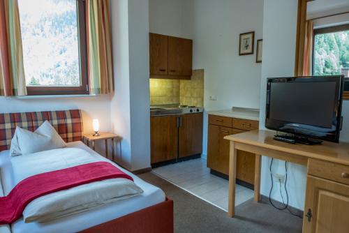 a small room with a bed and a television at Hotel Kärntnerhof in Mallnitz