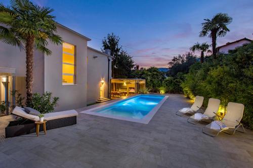 une arrière-cour avec une piscine et quelques palmiers dans l'établissement Villa Lovran, heated pool and Spa, à Lovran