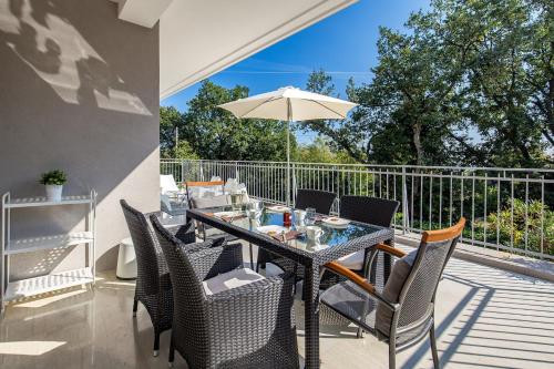 a patio with a table and chairs and an umbrella at Villa Lovran, heated pool and Spa in Lovran