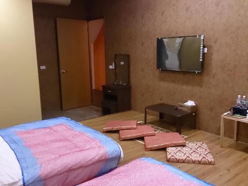 a room with a bed and a flat screen tv at Exotic Wind Sand City 86台東民宿 編號1368 in Taitung City