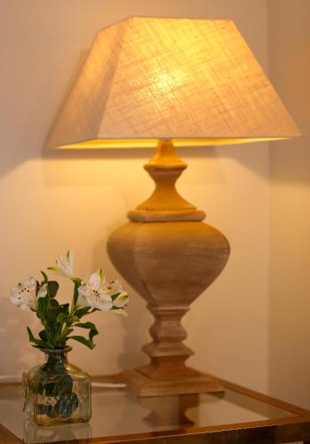 a lamp on a table next to a vase with flowers at La Ermita de Deva in Deva