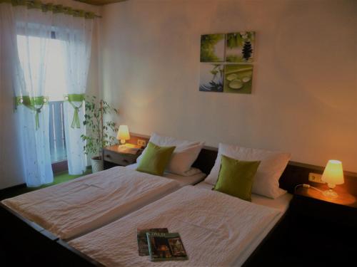 a bedroom with a bed with white sheets and green pillows at Landhaus Harmonie in Arnbruck