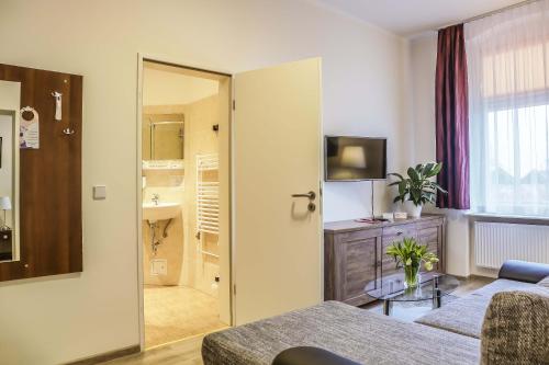 a living room with a couch and a table and a bathroom at City Residence Hotel Frankfurt-Oder Bahnhof in Frankfurt/Oder