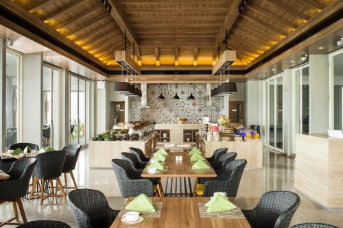 a restaurant with wooden ceilings and tables and chairs at Hotel Santika Premiere Beach Resort Belitung in Sijuk