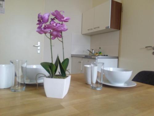 una mesa con una flor púrpura en un jarrón blanco en Apartmentpension am Stadtschloss, en Potsdam