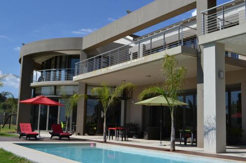 a building with a swimming pool with chairs and tables at Dante Deo Guesthouse in Bloemfontein