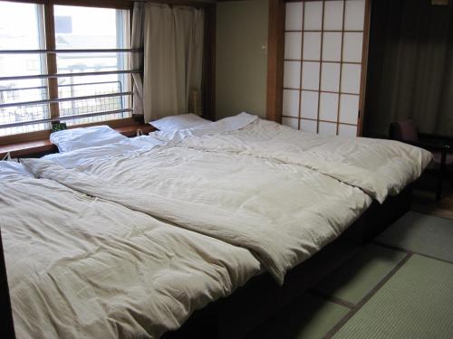 a large white bed in a room with a window at Hotel Viva Nikko in Nikko