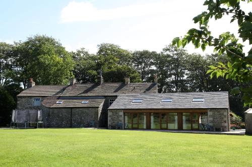 an old stone house with a green lawn in front of it at Green Grove Country House in Malham