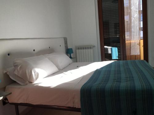 1 dormitorio con 1 cama con sábanas blancas y ventana en Le case di Pone en Cologno Monzese