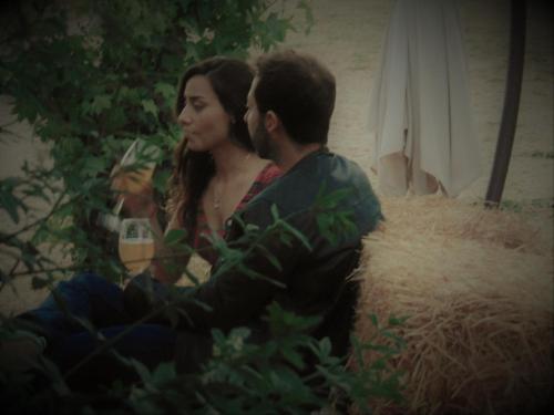a man and a woman sitting next to a haystack at Cabañas Puente Negro in Puente Negro