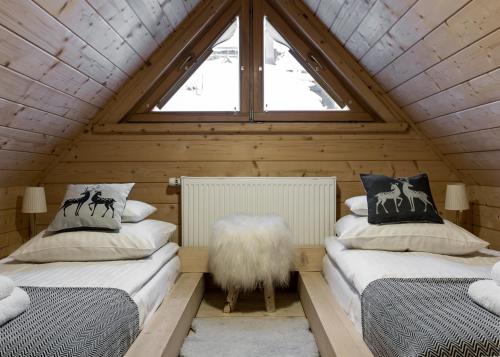 two beds in a attic room with a window at Domki pod Gubałówką in Zakopane