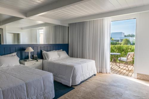a hotel room with two beds and a balcony at Green Village Hotel e Restaurante in Santa Bárbara do Rio Pardo