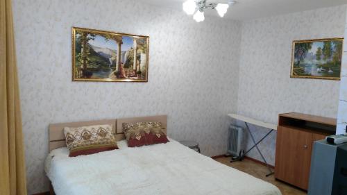 ペルミにあるStudio u Permskoy Yarmarkiのベッドルーム1室(ベッド1台付)が備わります。壁に2枚の写真が飾られています。