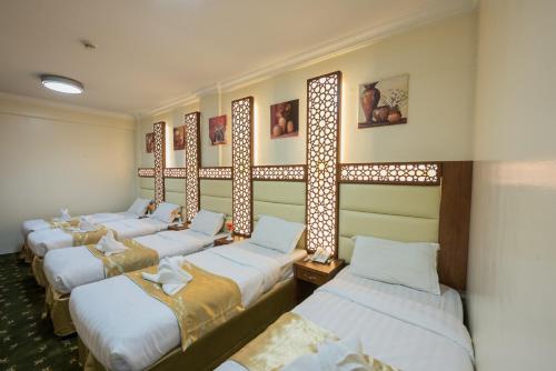 4 camas en fila en una habitación en Rawdhat Al Mukhtara Hotel, en Medina