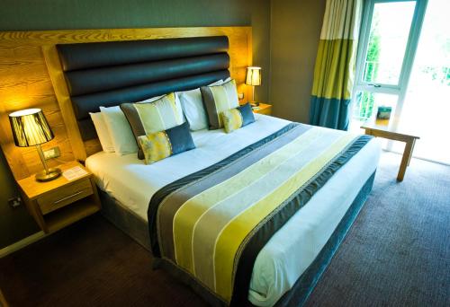 a hotel room with a large bed with pillows at Thornton Hall Hotel & Spa in Heswall